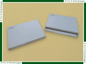 Boîtes en carton brut gris, fabrication artisanale traditionnelle avec coins agrafés, finition soignée incluant une sérigraphie d'un visuel de coloris noir dans le coin supérieur gauche